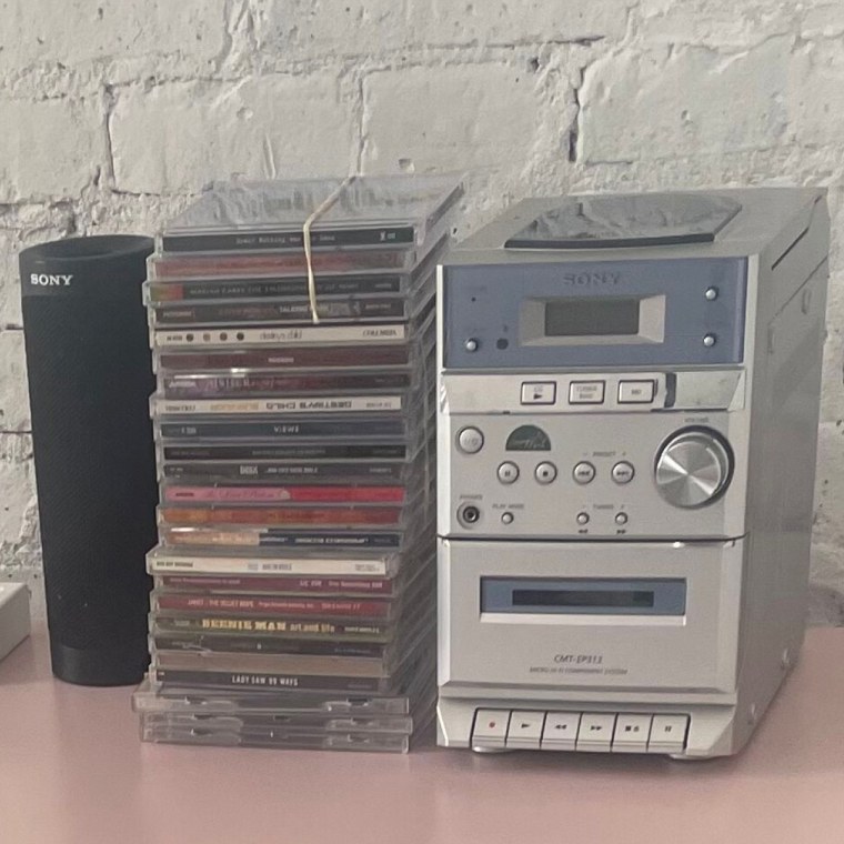 The Sony CMT-NE3 on a pink dresser beside a stack of CDs.