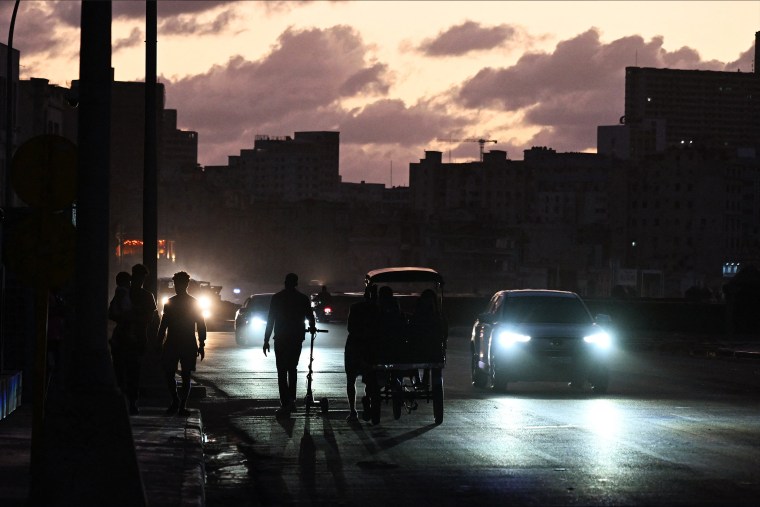 People transit on a street without power during a nation wide blackout in Havana on March 21, 2026. A power outage struck the entire island of Cuba on March 21, 2026, the energy ministry said, in the second nationwide blackout in less than a week as its grid struggles under a U.S. oil blockade.