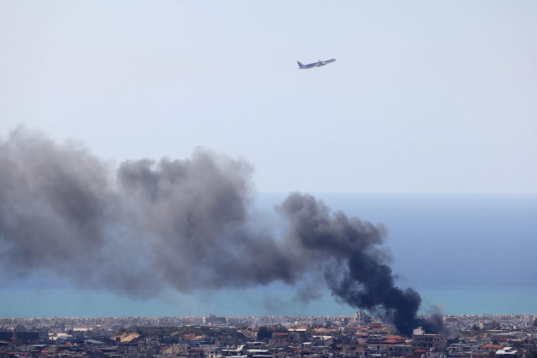 An aircraft takes off from Beirut Airport as smoke rises from the site of an Israeli airstrike Tuesday.