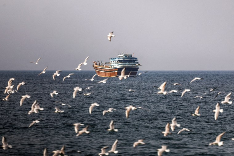 Birds fly near a boat in the Strait of Hormuz amid the U.S.-Israeli conflict with Iran, as seen from Musandam