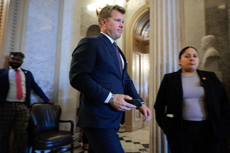Tim Sheehy walks in the US Capitol building with a mobile phone in his right hand.