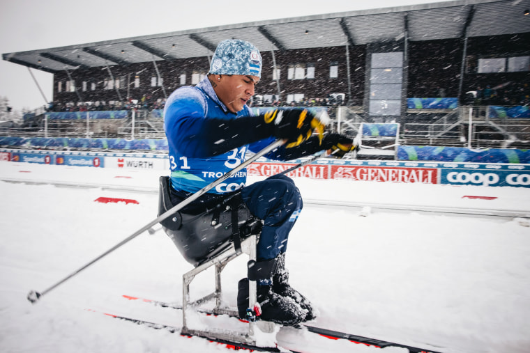 An image of a man cross-country skiing during heavy snowfall in a specialized chair mounted to two skis.