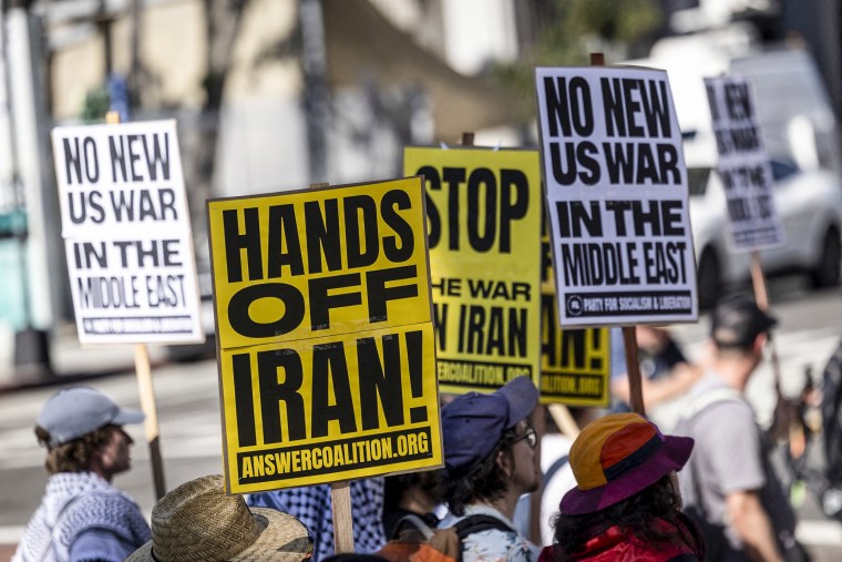 Image: Protesters hold placards during a demonstration against the war in Iran