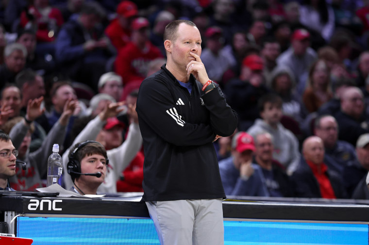 Travis Steele holds his chin while watching a basketball game from the sidelines.