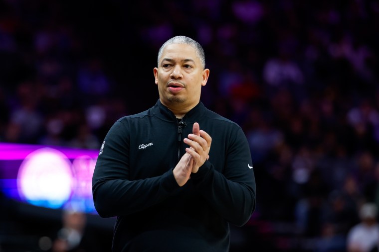 Tyronn Lue claps while standing on the court