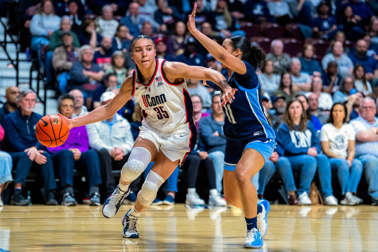 Two women basketball players on the court during gameplay.