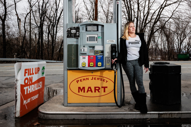 Amanda Robbins holds a gas pump at a gas station while posing for a portrait