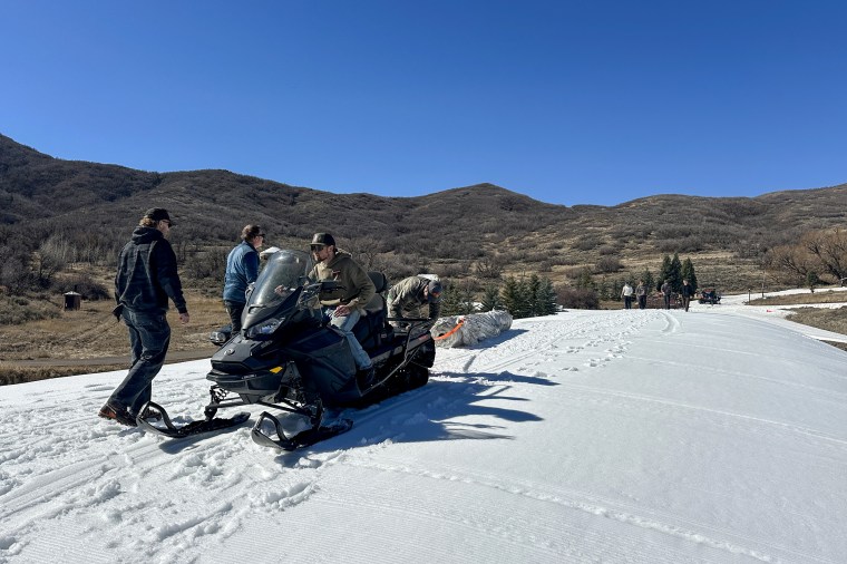 Soldier Hollow Nordic Center staff use a snowmobile to position Snow Secure over
the snow preservation pile.