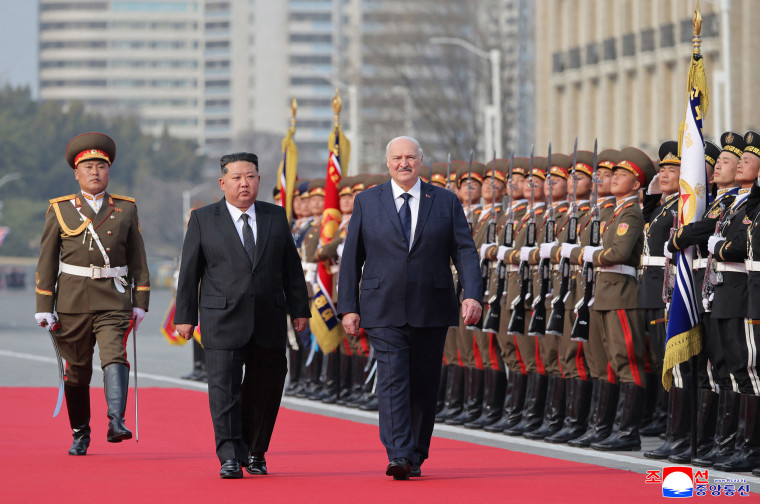 Image: Kim Jong Un and and Alexander Lukashenko inspecting honour guards whilst walking along a red carpet.