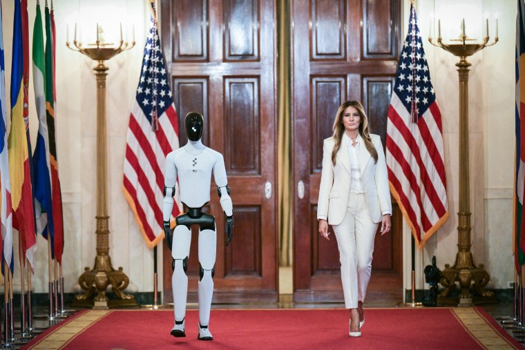 Image: First lady Melania Trump walks with a humanoid robot
