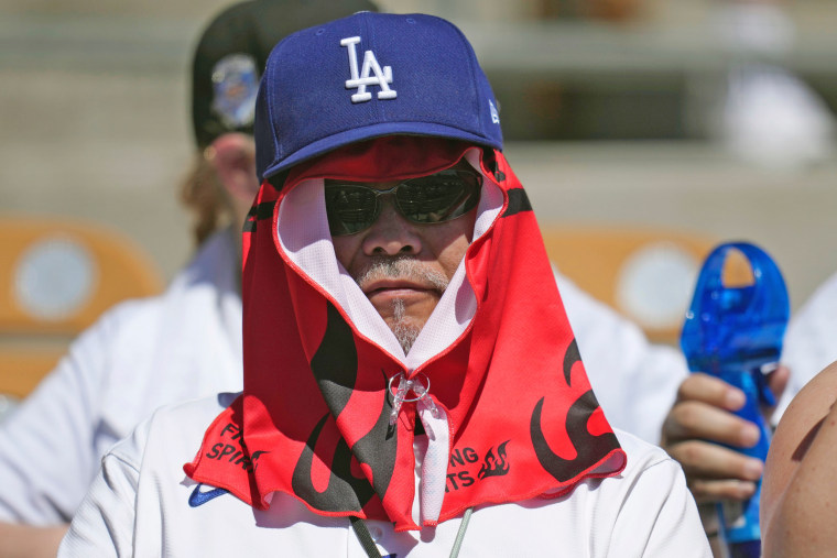 A Los Angeles Dodgers fan covers up from the hot sun during a spring training game on March 21, 2026, in Phoenix.