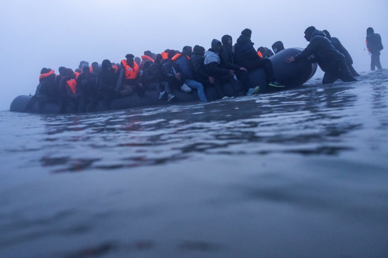 Smugglers assist people to board a boat in an attempt to cross the English Channel off the beach of Gravelines, northern France, on March 4.