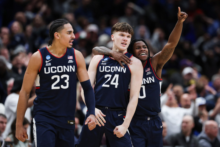 Braylon Mullins #24 comemora na quadra de basquete com Jayden Ross #23 e Malachi Smith #0 do UConn Huskies.