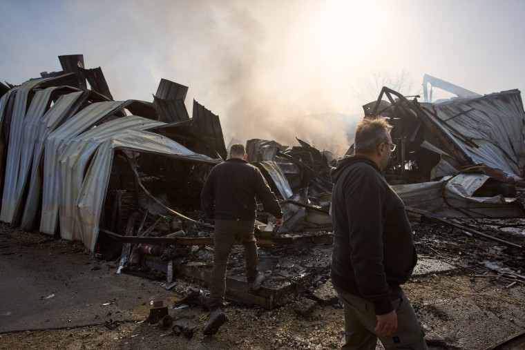 Varias personas inspeccionan el lugar donde un misil iraní impactó de lleno en el centro de Israel, el 18 de marzo de 2026.
