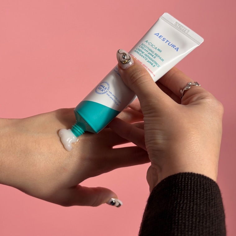 Woman applying cream to the back of hand from a tube