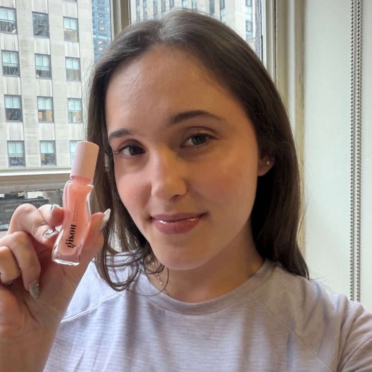 Woman showing lip oil after apply it to lips