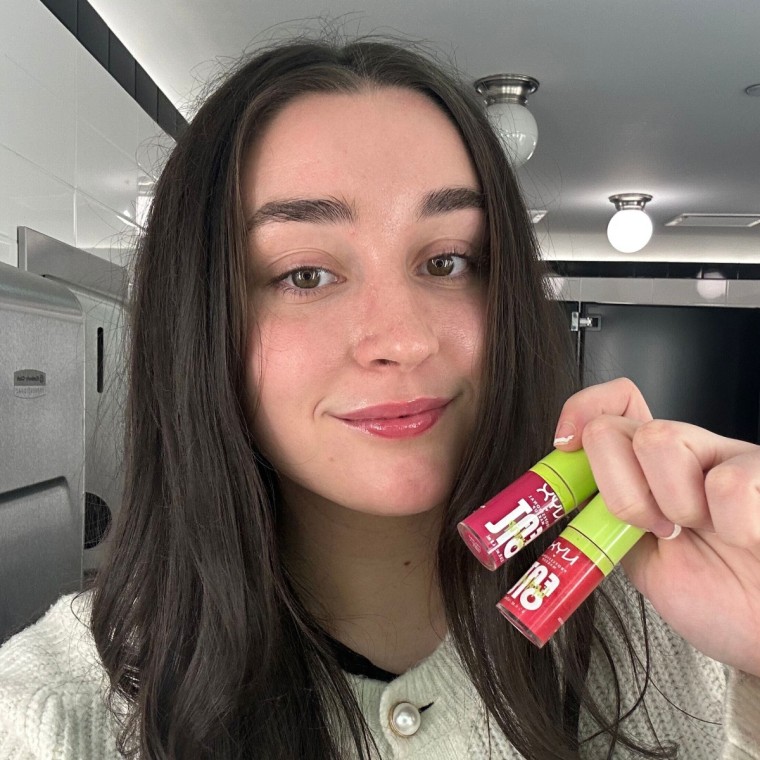 Woman holding two lip balms after applying them