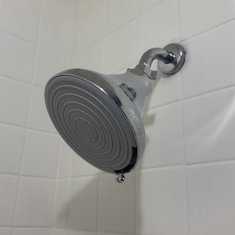 A silver Nuud No1 Filtered Showerhead installed in a bathroom.