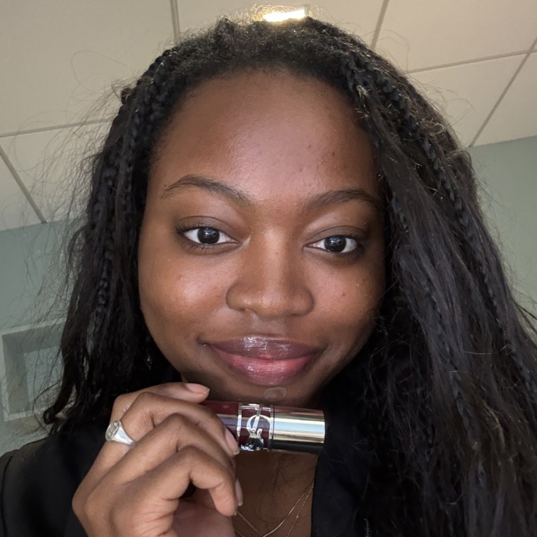 Woman holding plumping lip oil after applying to her lips