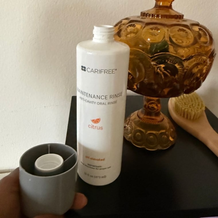 White bottle of Carifree mouthwash on a black desk.