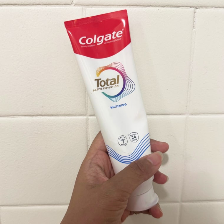 Hand holds a tube of Colgate Total Active Prevention Whitening Toothpaste