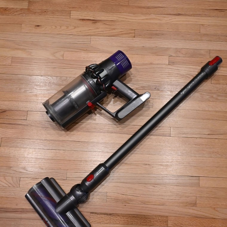 Dyson V10 cordless vacuum on a hardwood floor.