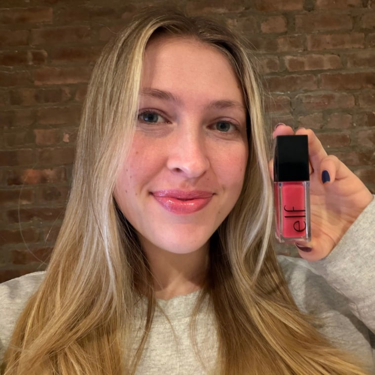 Woman holding up lip oil after applying to her lips