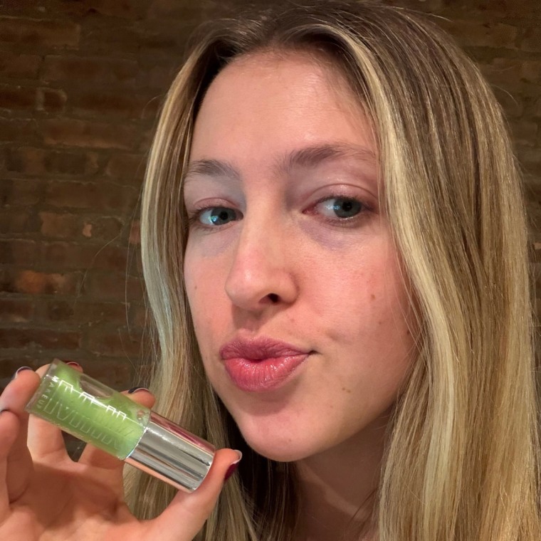 Woman holding lip oil after applying it