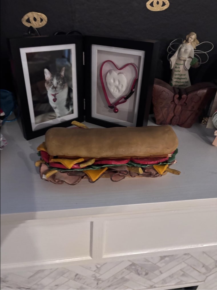 Sandwiches the cat in his urn on the mantel.