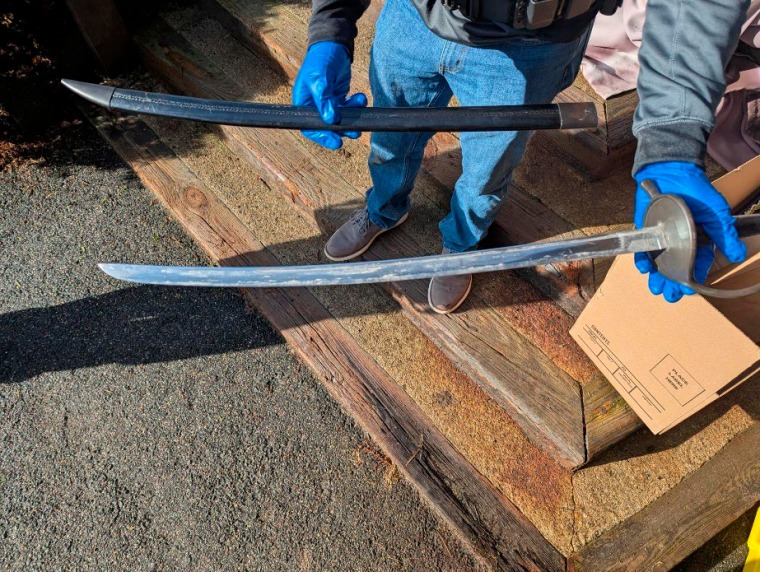 scam detection A man, seen from the waist down, holds a sword and sheath in either hand.