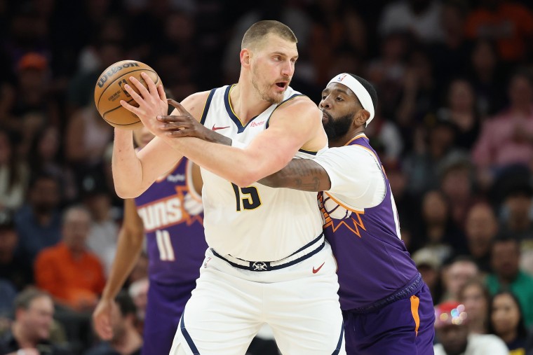 Nikola Jokic of the Denver Nuggets handles the ball under pressure from Royce O'Neale of the Phoenix Suns 