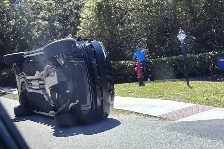 Golfer Tiger Woods stands by his overturned vehicle in Jupiter Island, Fla., on March 27, 2026. 