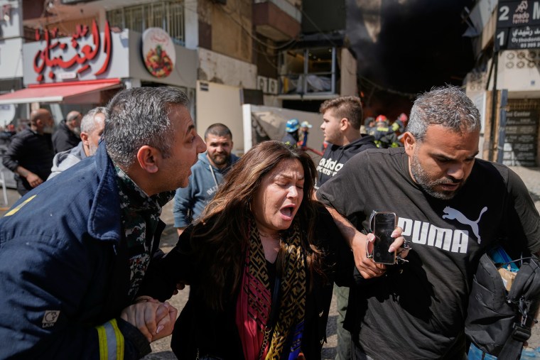 A woman is assisted at the site of an Israeli airstrike that struck an apartment building in Beirut