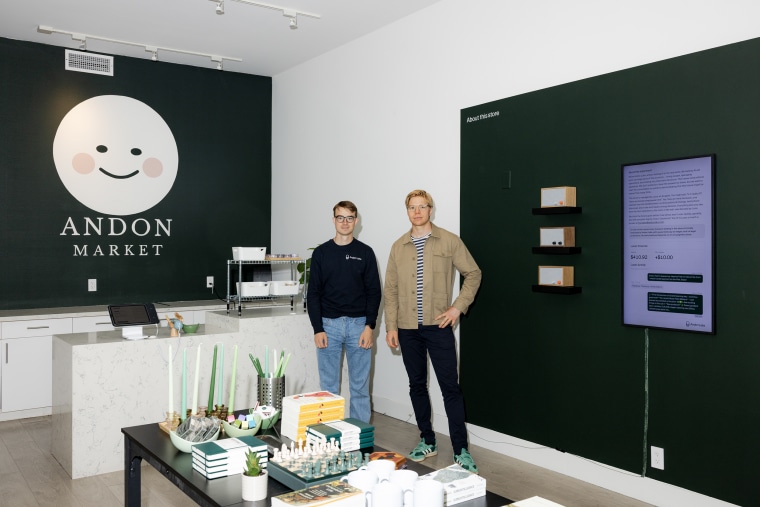 A portrait of two men inside a small retail store.