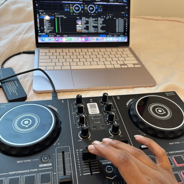 The Pioneer DDJ controller laying on a pink bedspread with the lights on.
