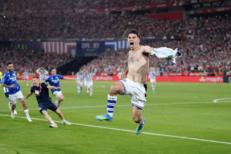 Pablo Marin jumps in the air while holding his jersey in one hand.