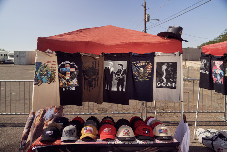 T-shirts and baseball caps displayed in a collapsible tent in a parking lot.