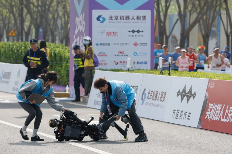 Technicians attend to a humanoid robot after a fall during the 2026 Beijing E-Town Humanoid Robot Half-marathon on April 19.