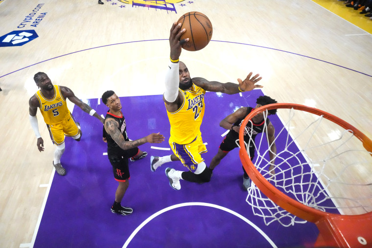 LeBron James salta para lançar uma bola de basquete no aro