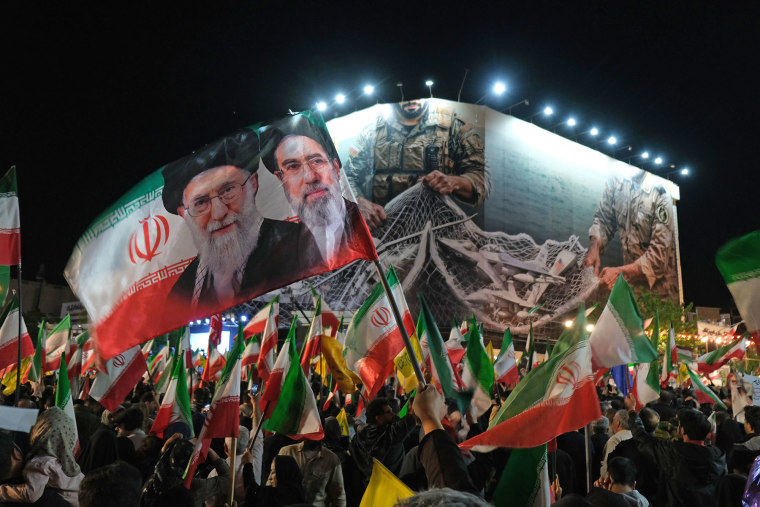 Iranians rally under a huge banner proclaiming that the Strait of Hormuz will remain closed