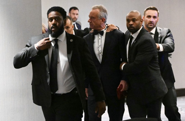Secretary of Health and Human Services Robert F. Kennedy Jr. is rushed out by Secret Service agents after loud bangs were heard during the dinner on Saturday night.