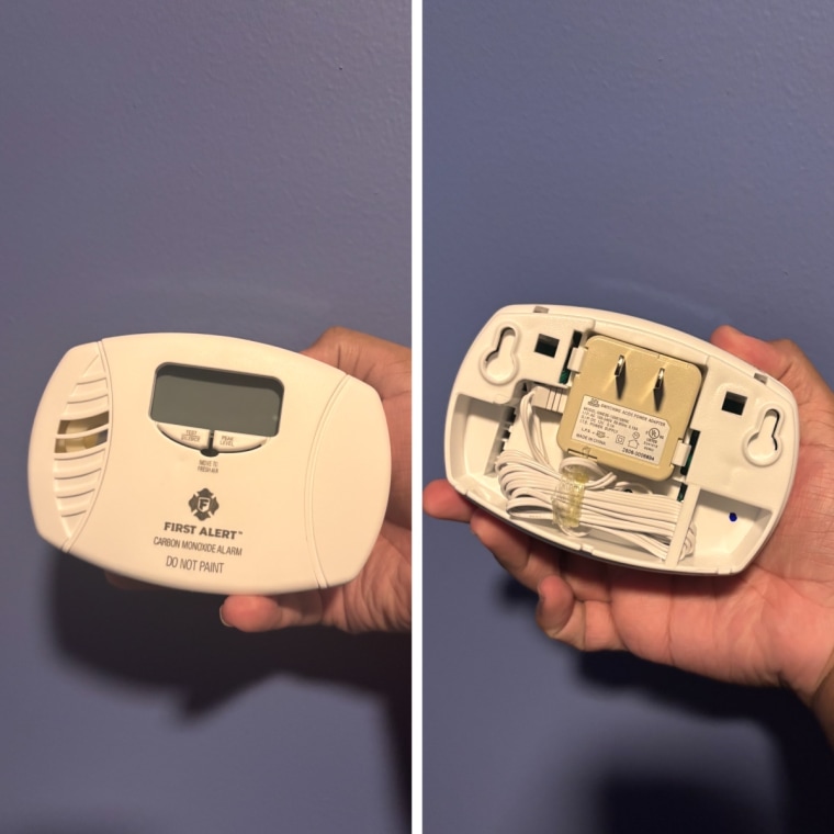Person holding and showing the back of the First Alert CO615 Dual-Power Plug-In Carbon Monoxide Detector.
