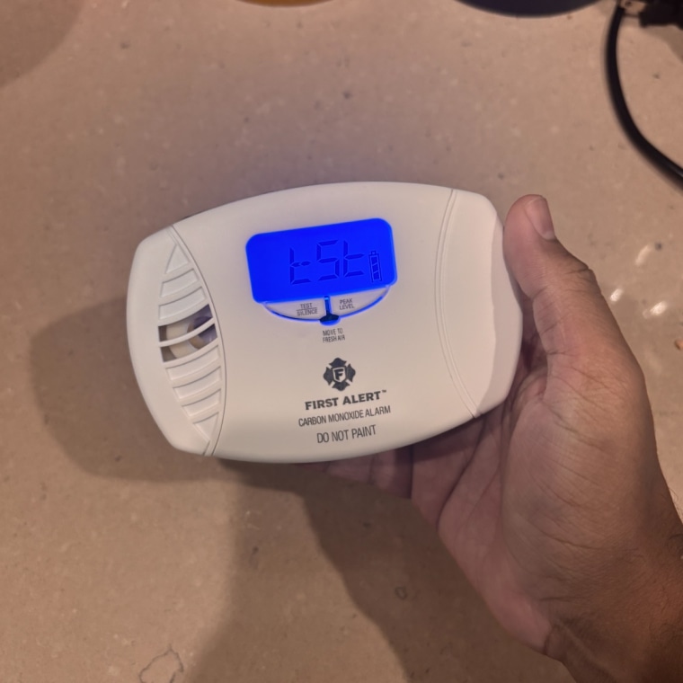 Person holding First Alert CO615 Dual-Power Plug-In Carbon Monoxide Detector with right hand.
