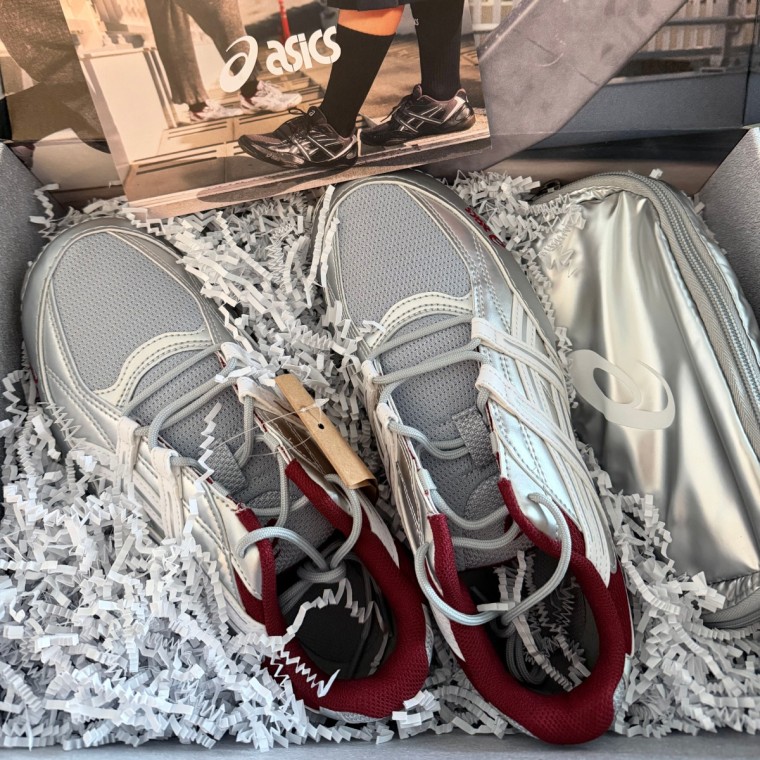 Silver ASICS shoes in a PR box with white confetti.