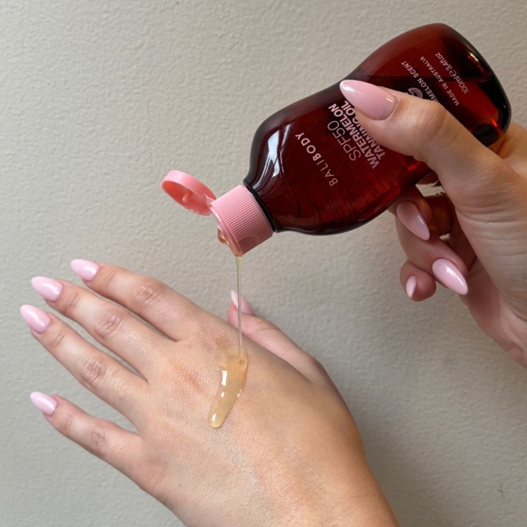Woman applying sunscreen oil on back of hand