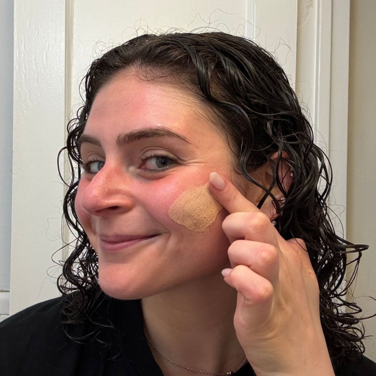 Woman applying tinted sunscreen on her face