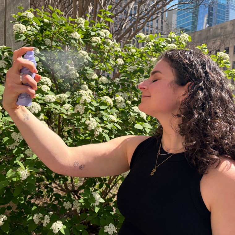 Woman spraying sunscreen mist on face