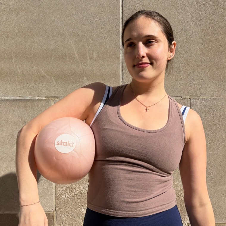 Woman in activewear holding pink Pilates ball