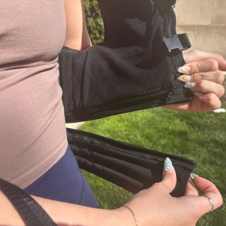 Woman holding removable panel on weighted vest