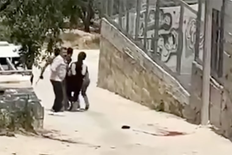 Aws al-Nasaan is carried after being shot in the West Bank village of Al-Mughayyir. A pool of blood lies on the floor. 